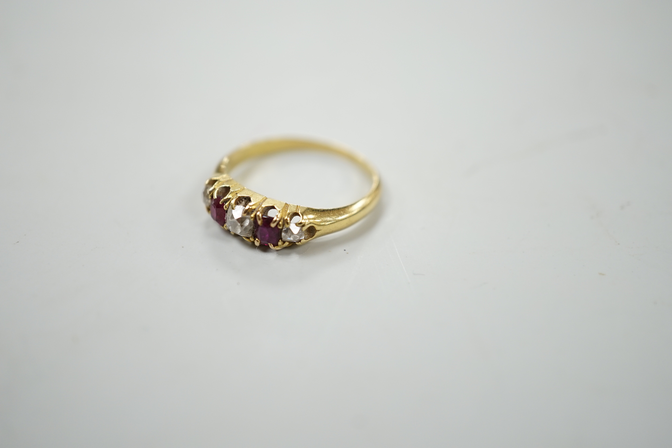 A yellow metal, two stone ruby and three stone diamond set half hoop ring, size J, gross weight 2.2 grams.
